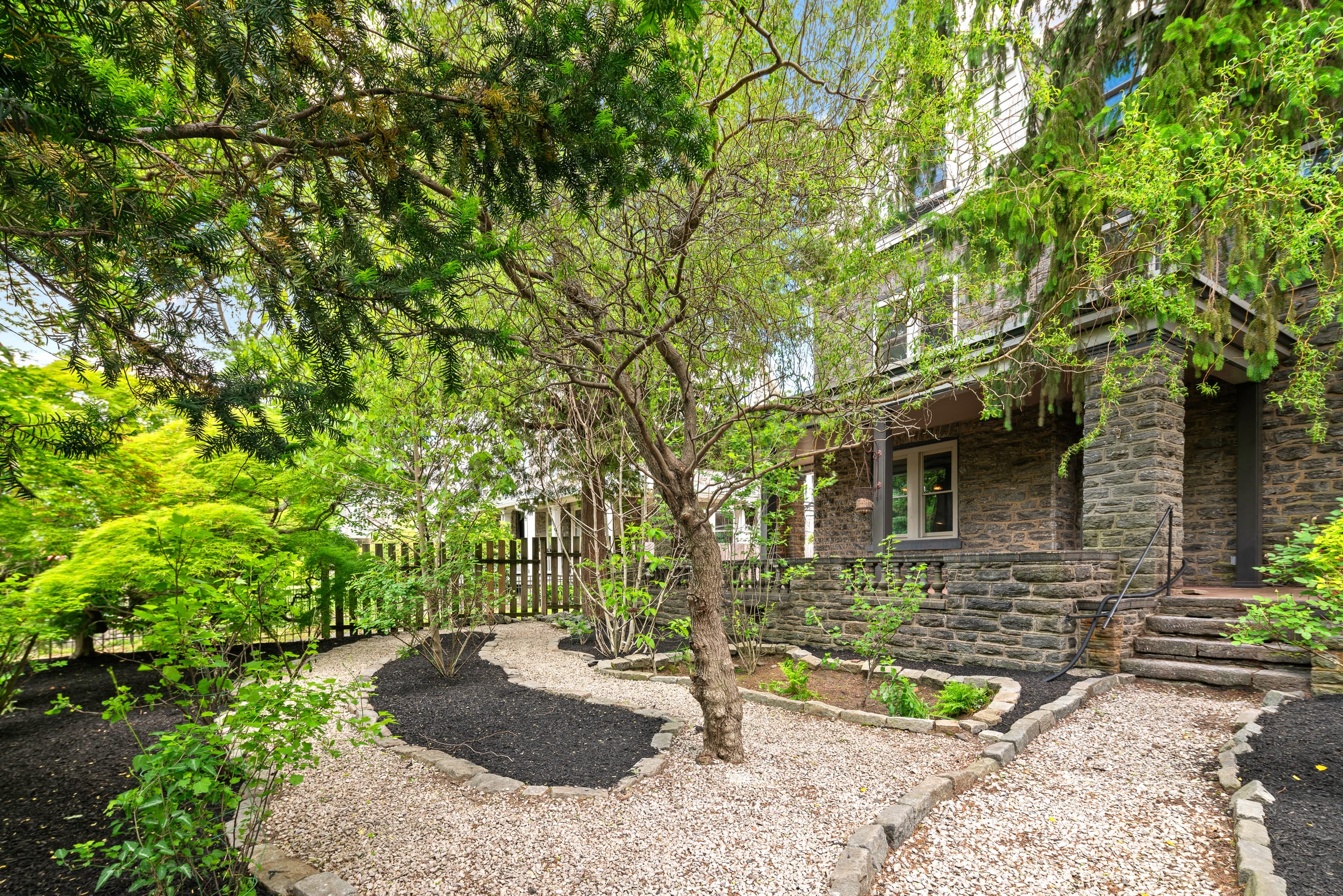 112 West Upsal Street — stone facade framed by mature gardens